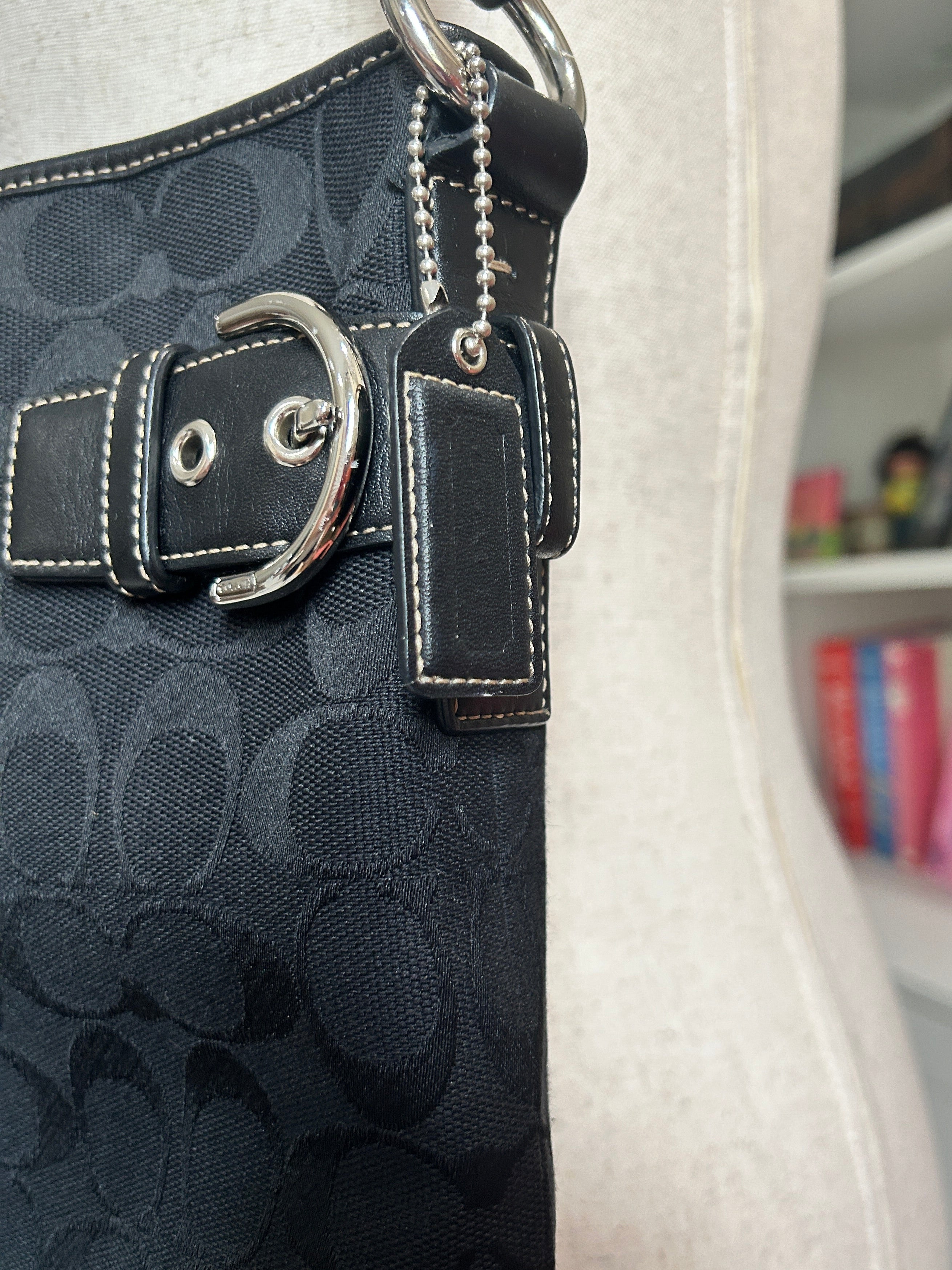 Black patterned handbag with silver buckle on a white surface