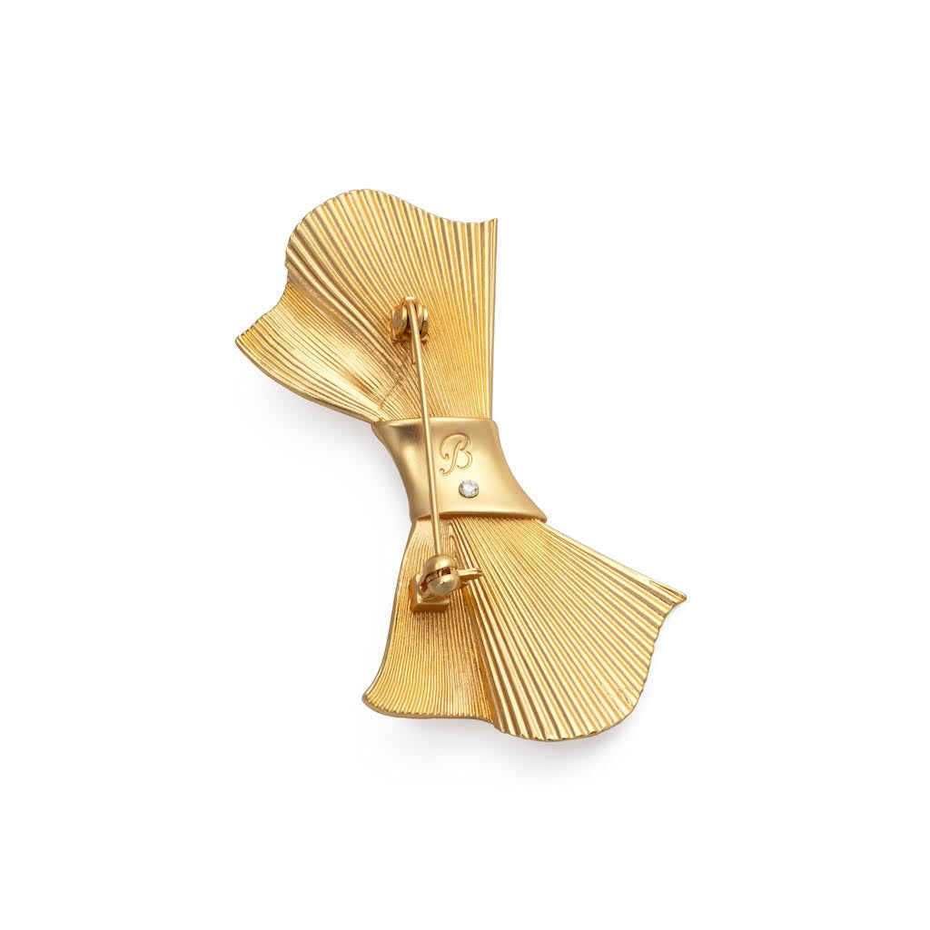 Gold bow-shaped brooch on a white background